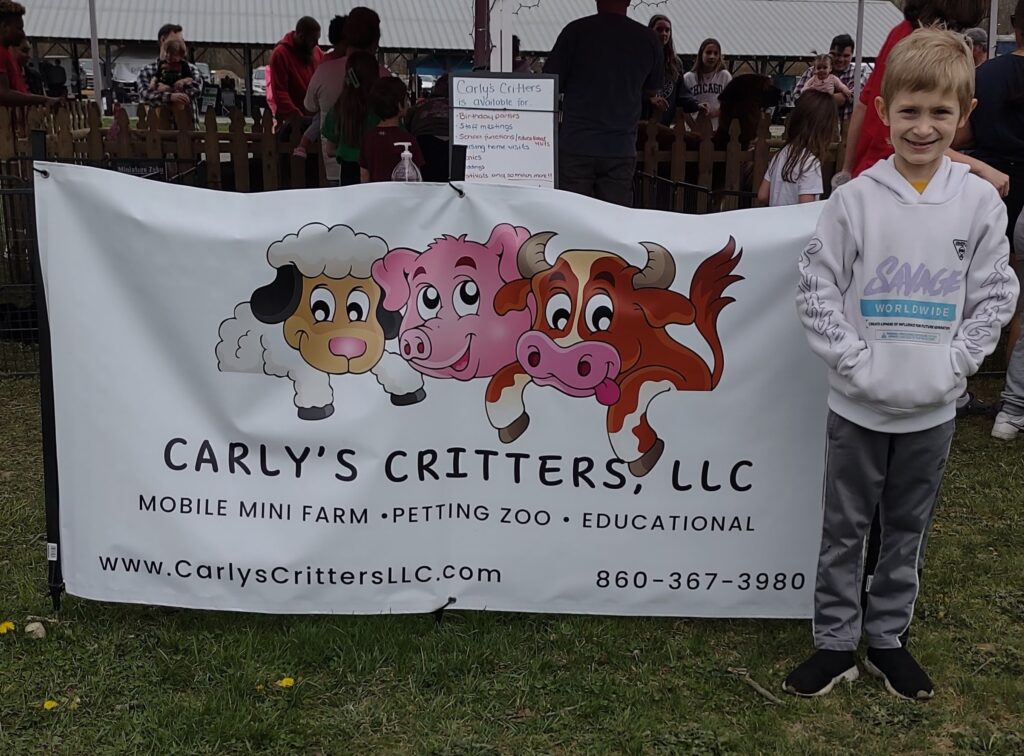 The halfling next to a sign for Carly's Critters.