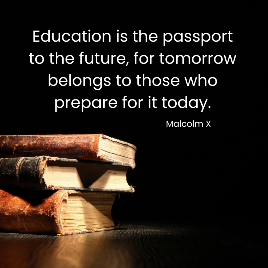 A light shines on a stack of old books sitting on a table. In the darkness above the books is a quote from Malcolm X. Education is the passport to the future, for tomorrow belongs to those who prepare for today.