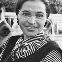 A black and white image of Rosa Parks wearing a striped shirt and plain color vest. 